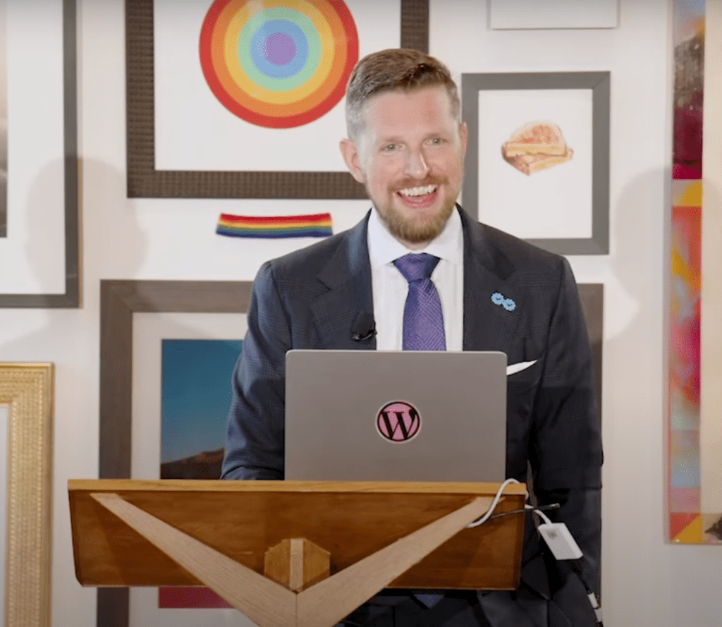 Matt Mullenweg at State of the Word 2022 against a backdrop of art pieces including a few from the Museum of Block Art.